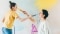 The image shows a woman and a child painting the walls.